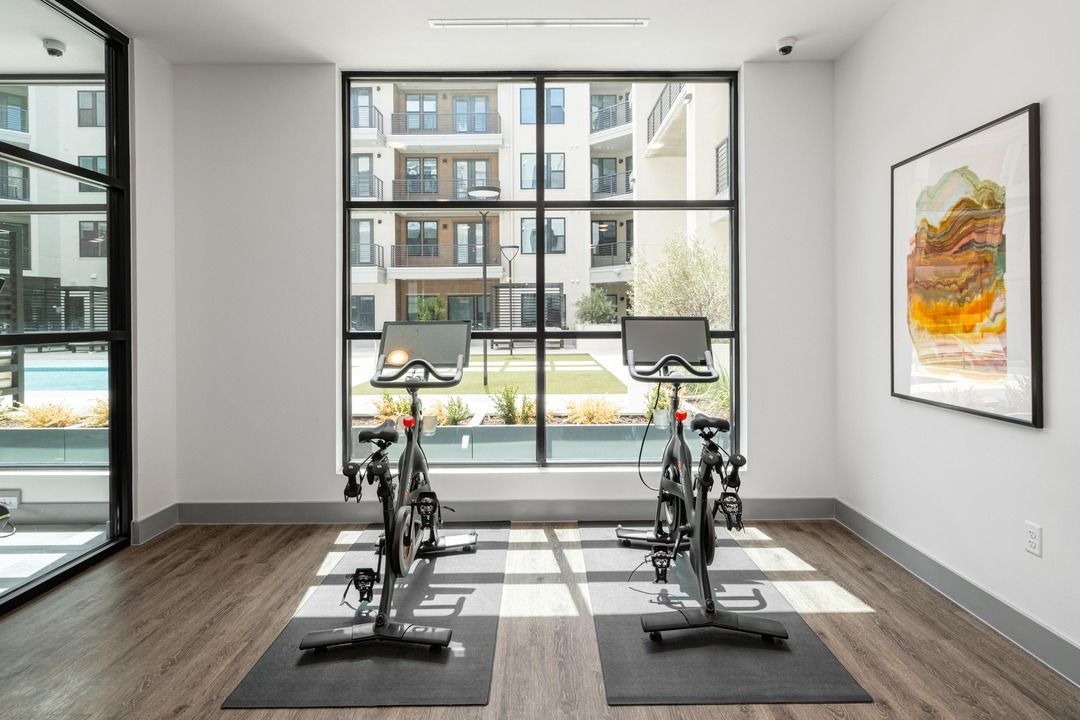 Spin studio with two Peloton bikes facing floor-to-ceiling windows.