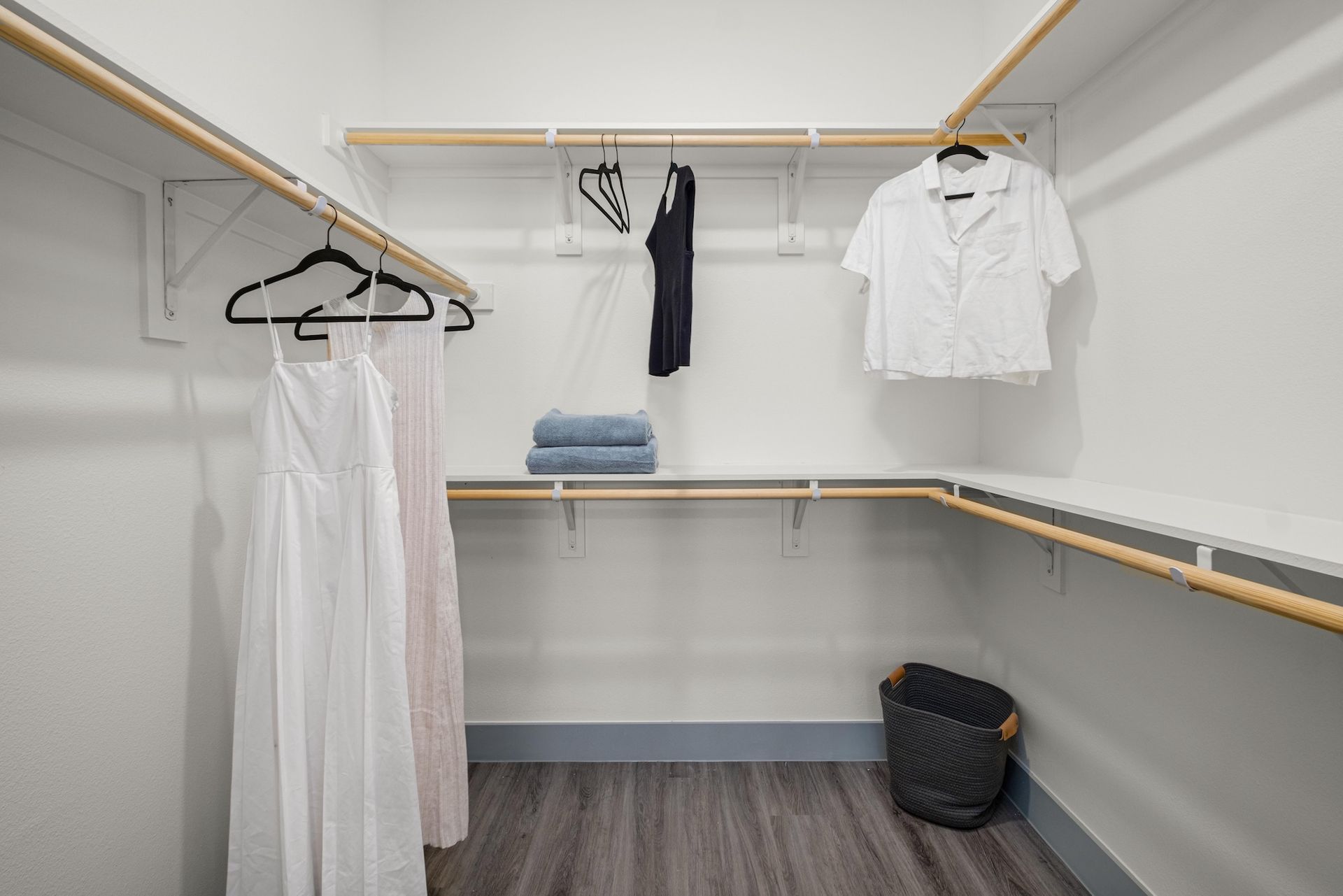 Walk-in closet with wood hanging rods, built-in shelving and a lower drawer bank.