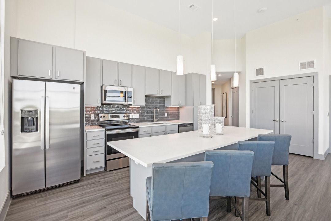 Penthouse kitchen with a stainless refrigerator, quartz island and blue upholstered bar seating.