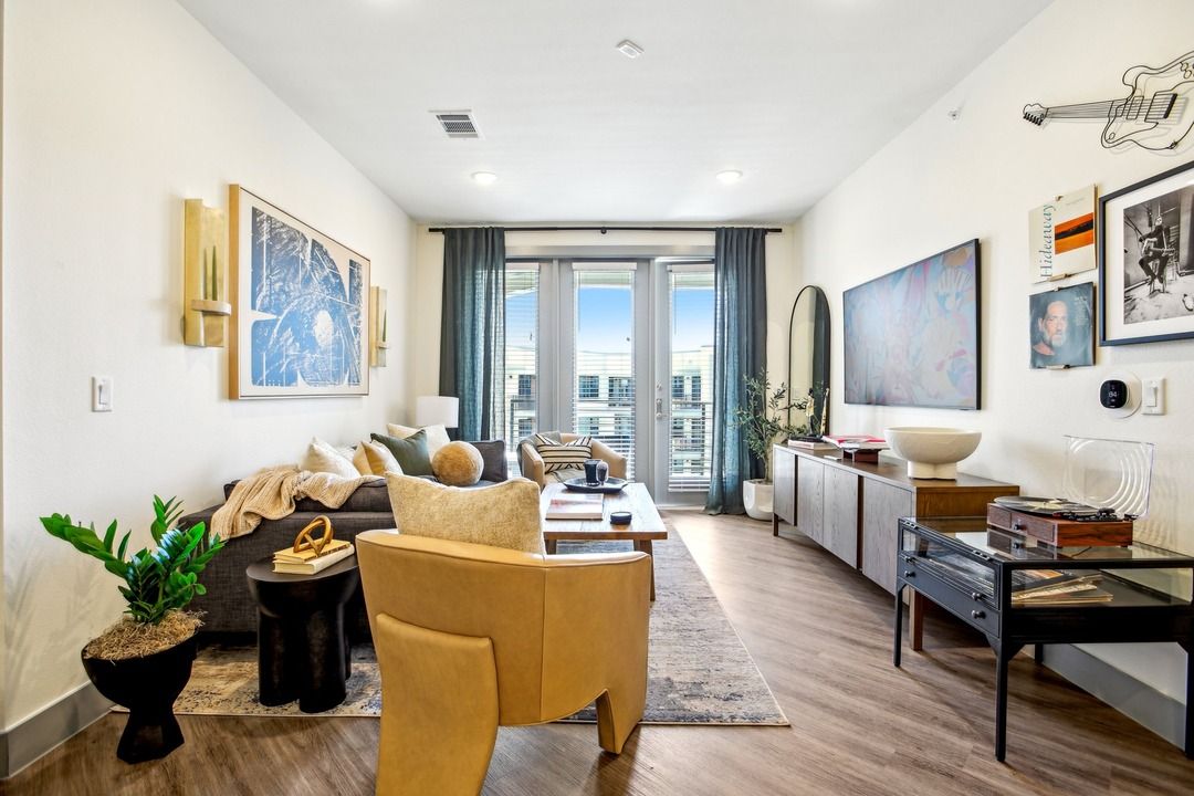 Apartment living room with a mustard accent chair, balcony access and a styled console table.