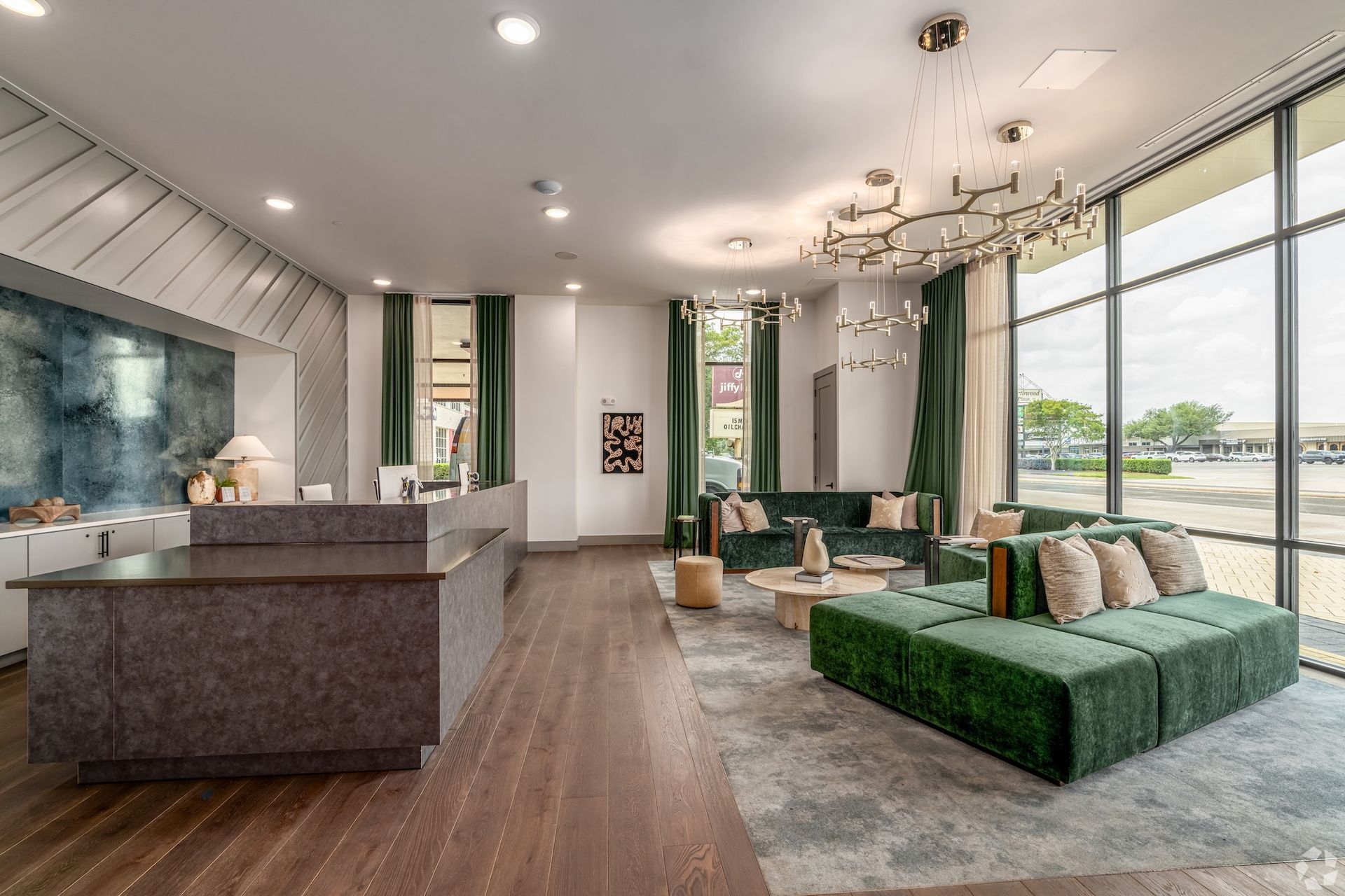 Resident clubhouse lounge with a green velvet sectional, chandelier and floor-to-ceiling windows.