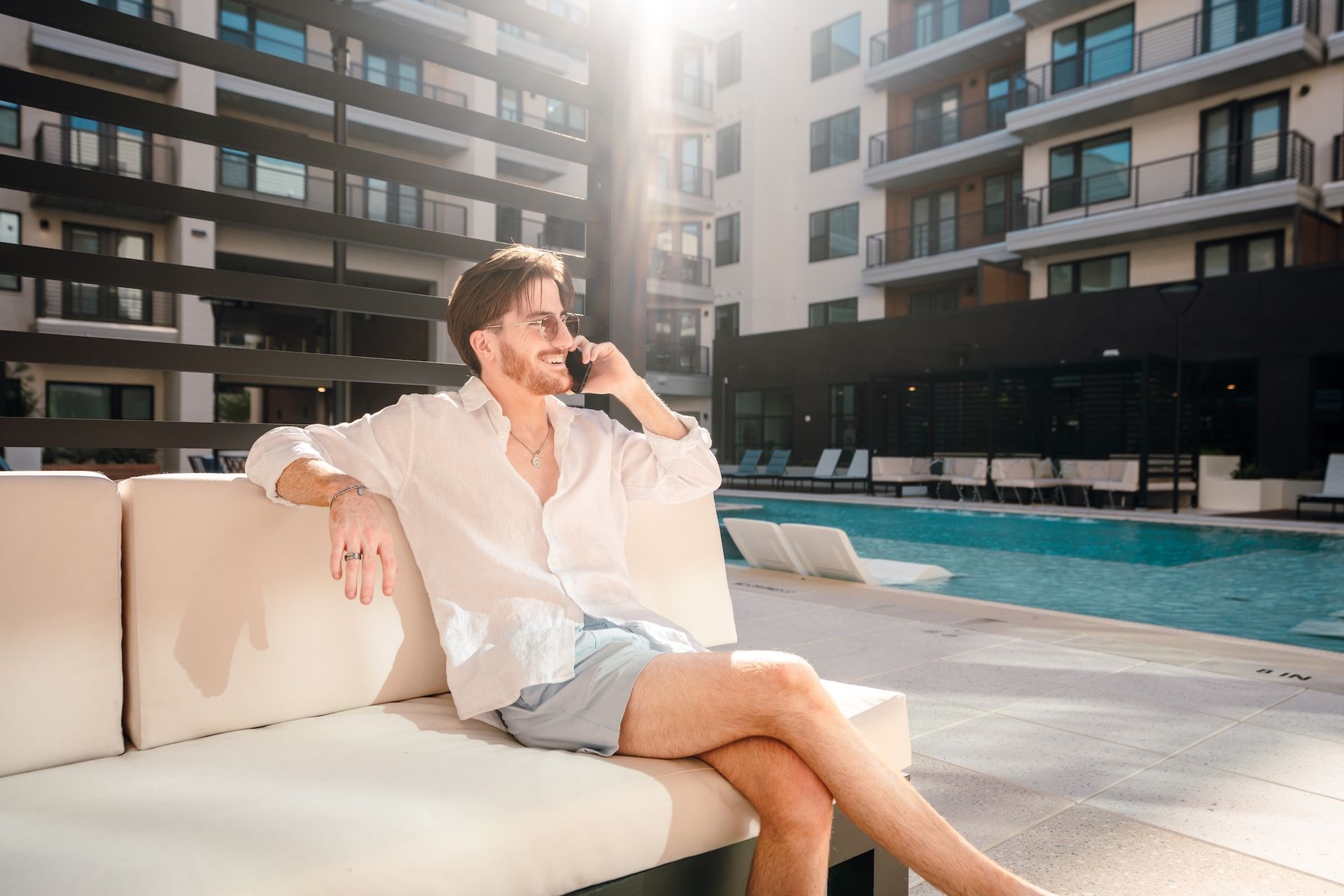 Resident relaxing on a poolside daybed with the courtyard and building behind.