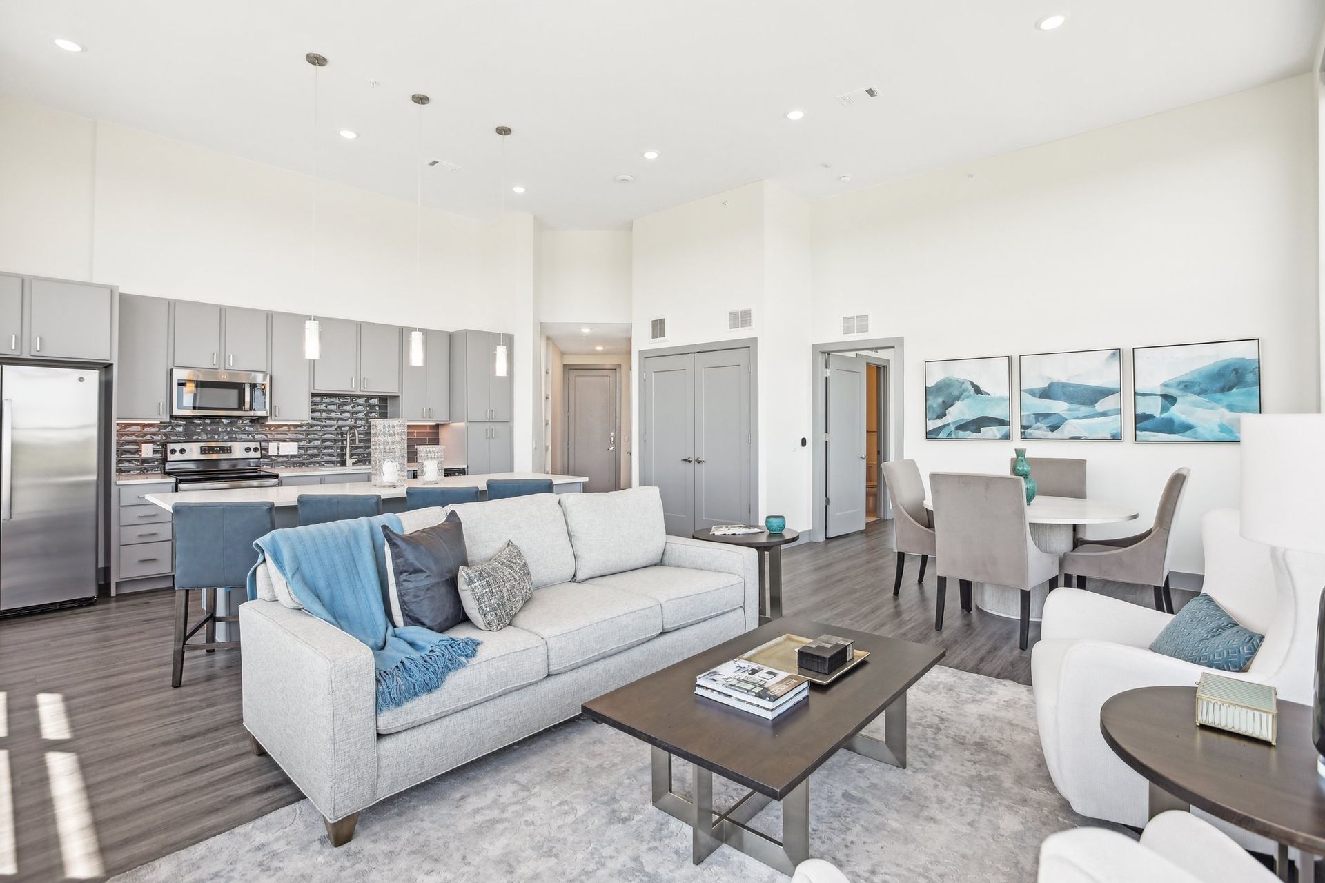 Penthouse living and dining space with sectional seating, a stainless kitchen and skyline windows.