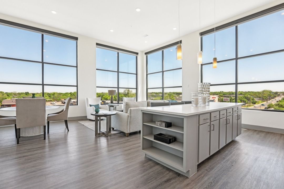 Penthouse living and dining space with floor-to-ceiling windows, a kitchen island and treetop views.