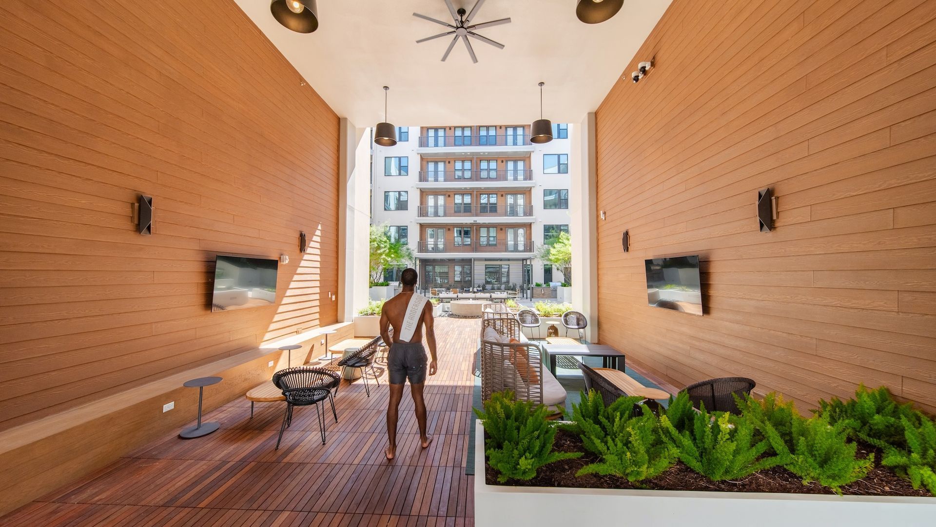 Covered breezeway lounge with wood walls, seating and planters opening onto the courtyard.