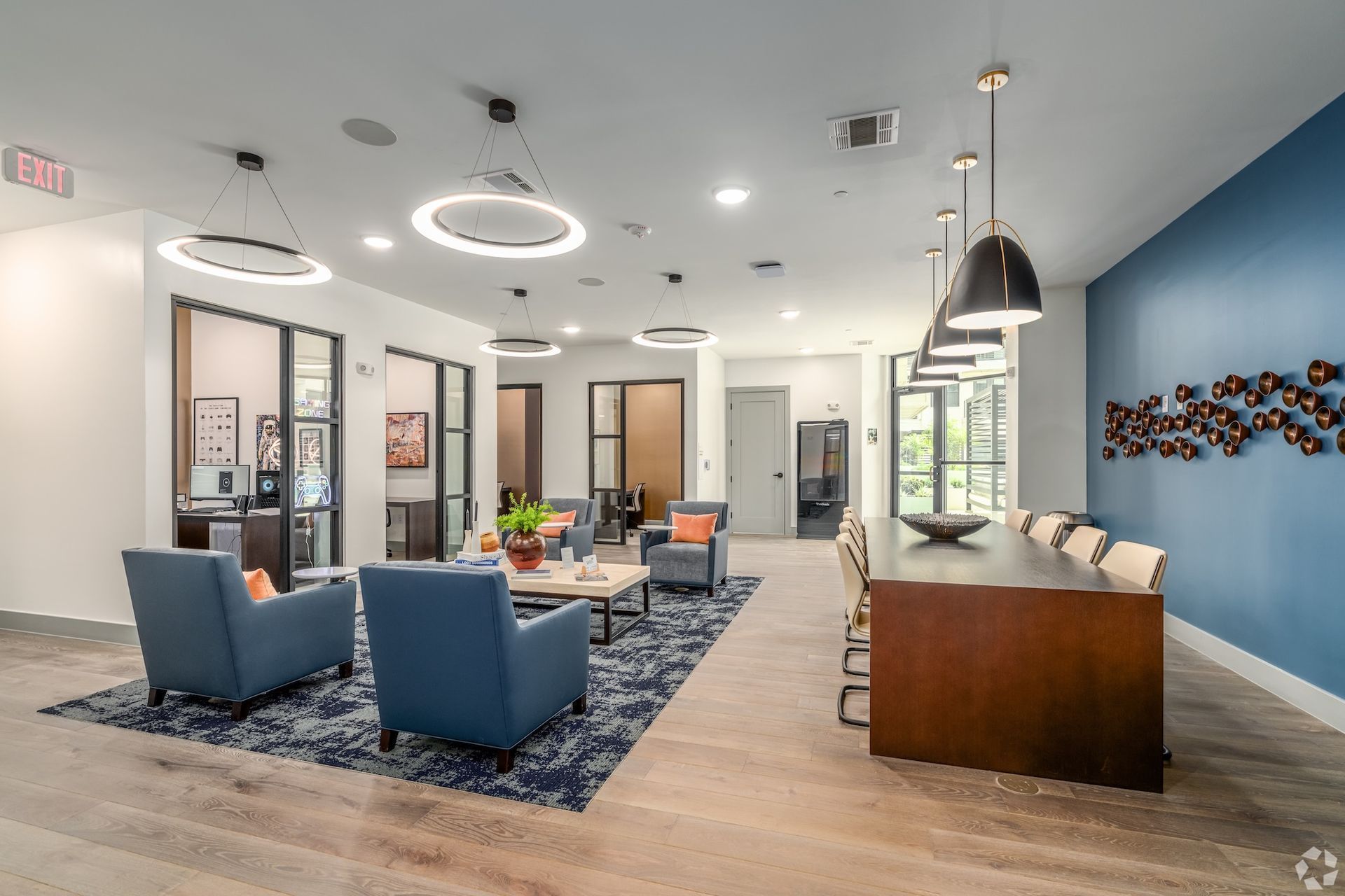 Leasing office lounge with blue armchairs, a wood reception desk and a decorative accent wall.