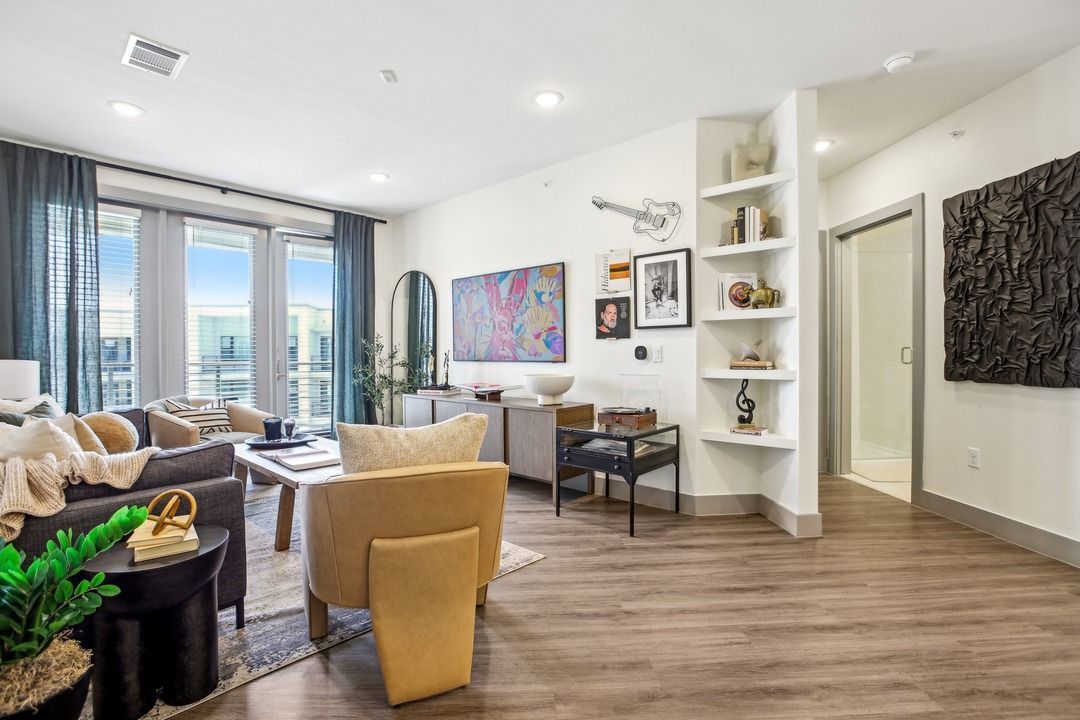 Open living and dining area with wood-look flooring, balcony doors and built-in shelving at The Anderson.