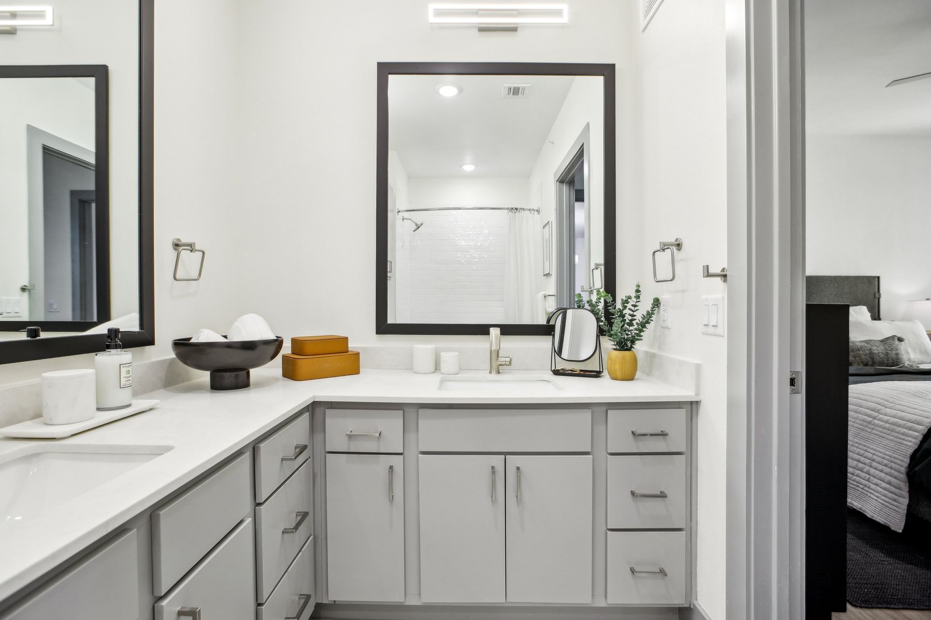 Bathroom with a double vanity, gray cabinets, quartz counter and framed mirrors.