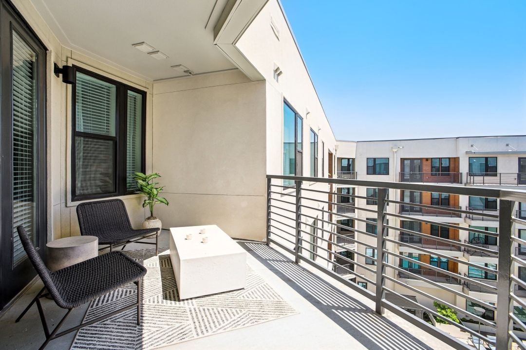 Private balcony with two lounge chairs and a side table overlooking the courtyard.