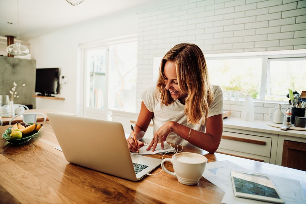 A woman is sitting at a table using a laptop computer.