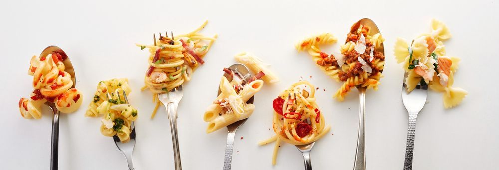 A pan filled with spaghetti and bacon on a table.