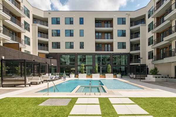 A large apartment building with a large swimming pool in front of it.