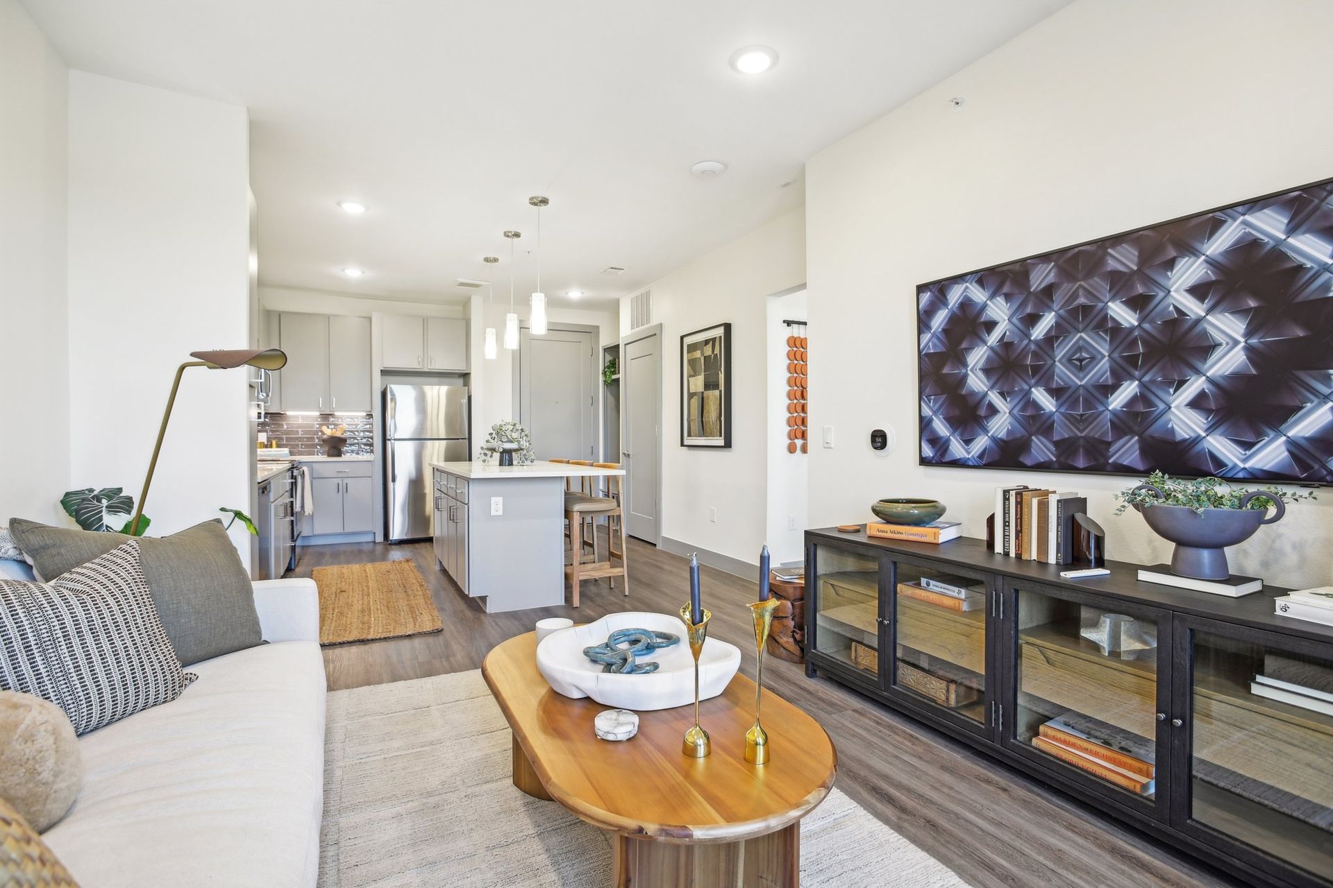 Modern living room with open kitchen, white walls, and wooden floors.