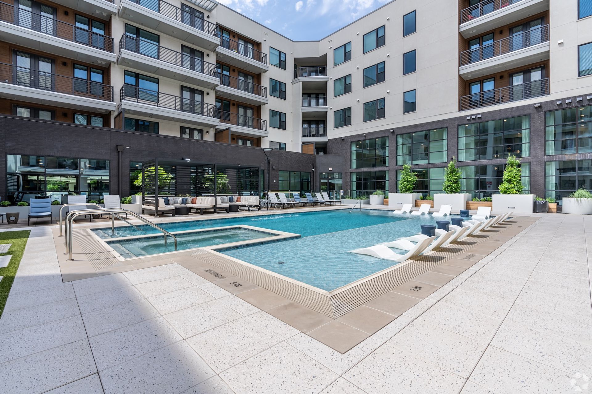 Resort-style courtyard pool surrounded by lounge chairs and the community's four-story facade.