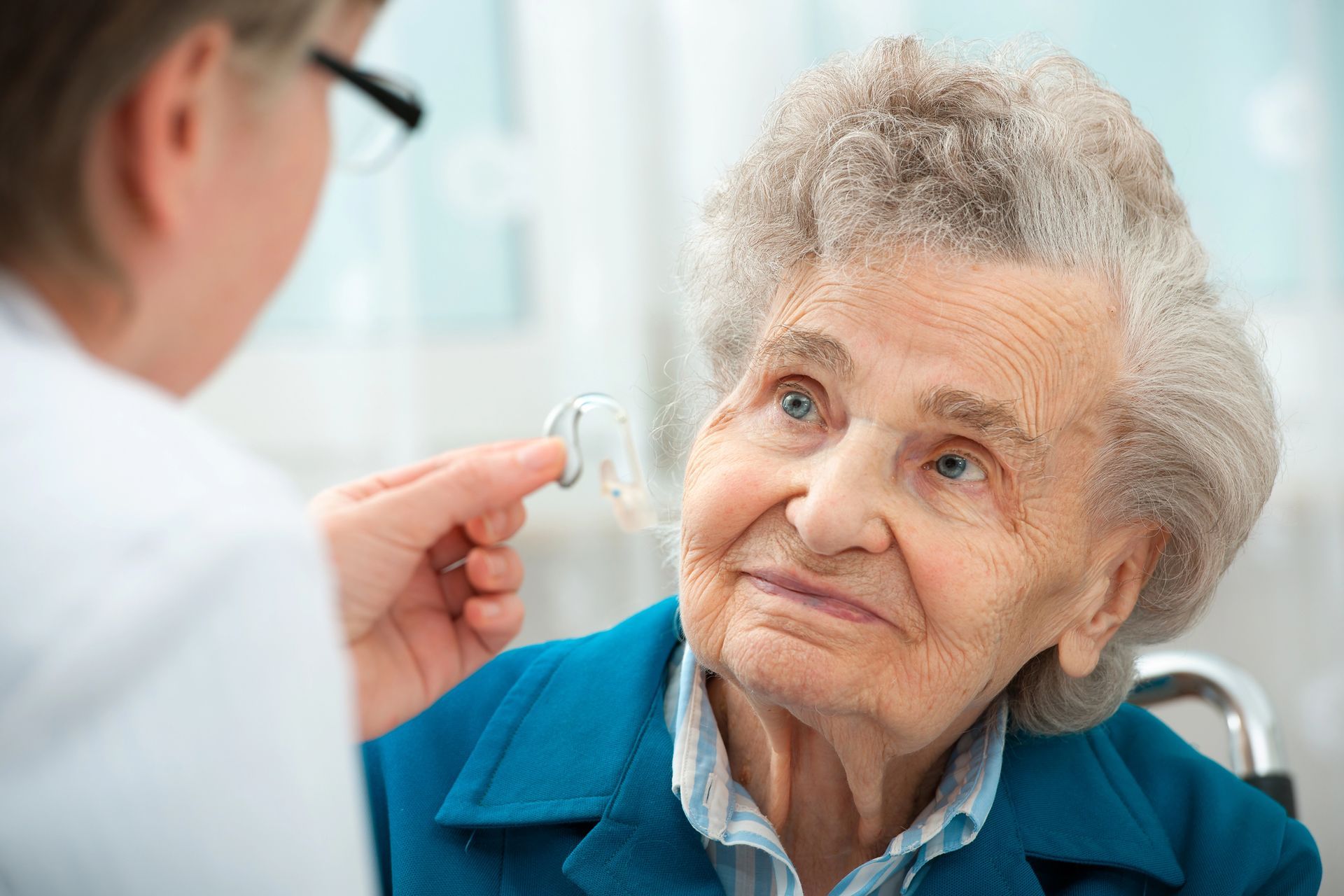 Un médico le muestra un audífono a un paciente anciano en la clínica.