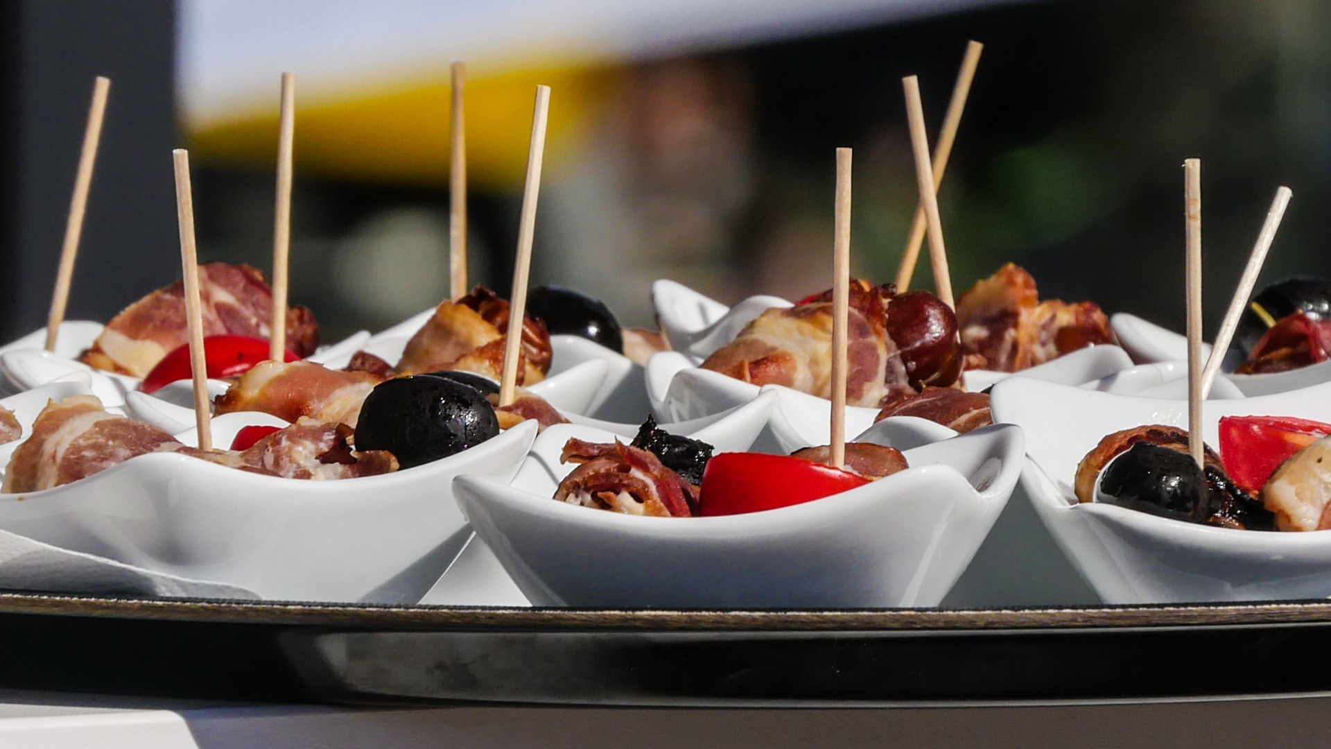 Dessert cups with whipped cream, berries, and chocolate on a tray at a buffet