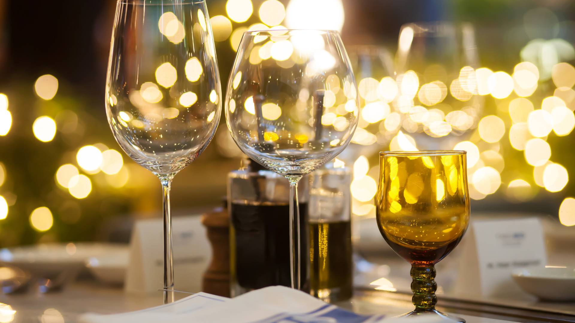 Wine glasses and amber glassware on a table with warm bokeh lights in the background
