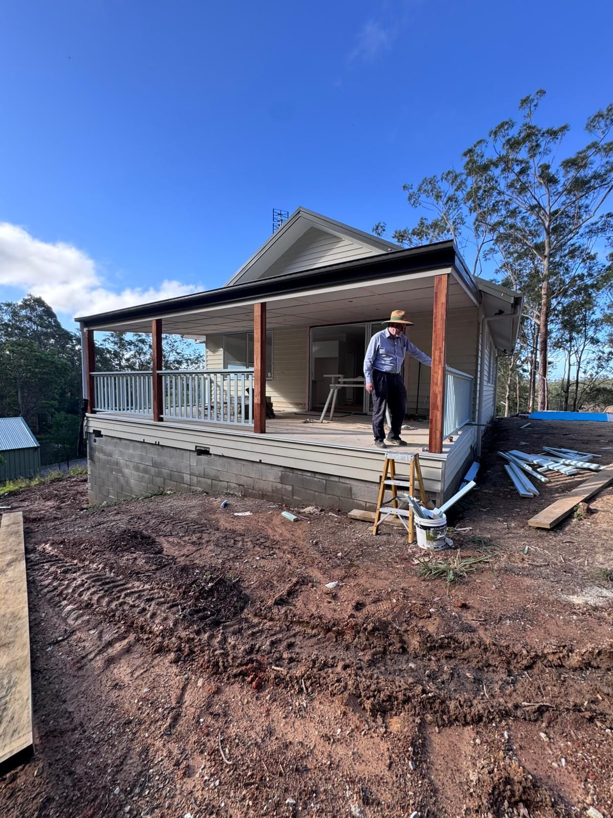 Construction site of a house; wooden beams and framing with a concrete floor and sunny sky.