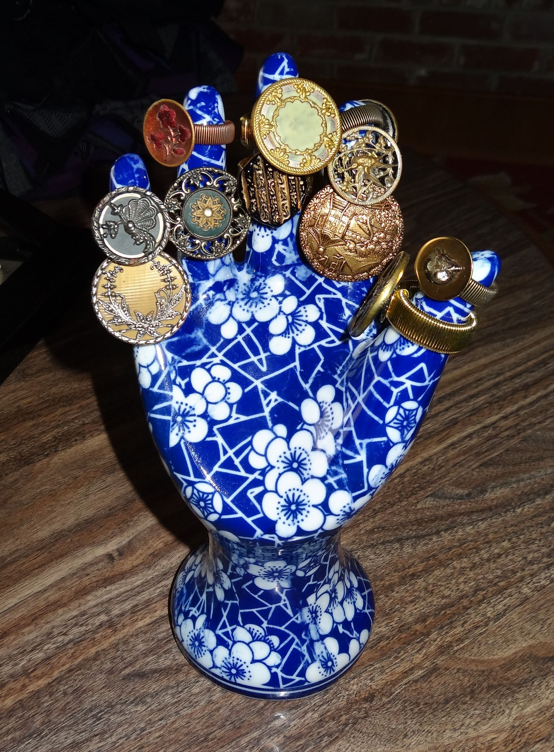 Blue and white ceramic hand-shaped ring holder, displaying various ornate rings.
