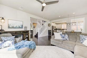 Holiday Decorating Bright modern living room with gray sofas, fireplace, staircase, and ceiling fan