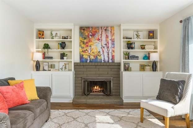 Living room with fireplace, bookshelves, artwork, sofa, and chair.