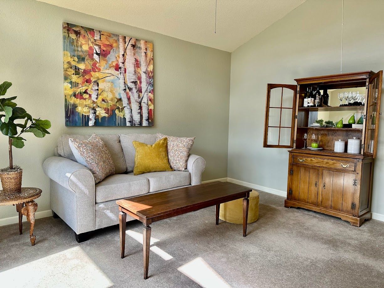 Living room with couch, art, antique bar, and coffee table.