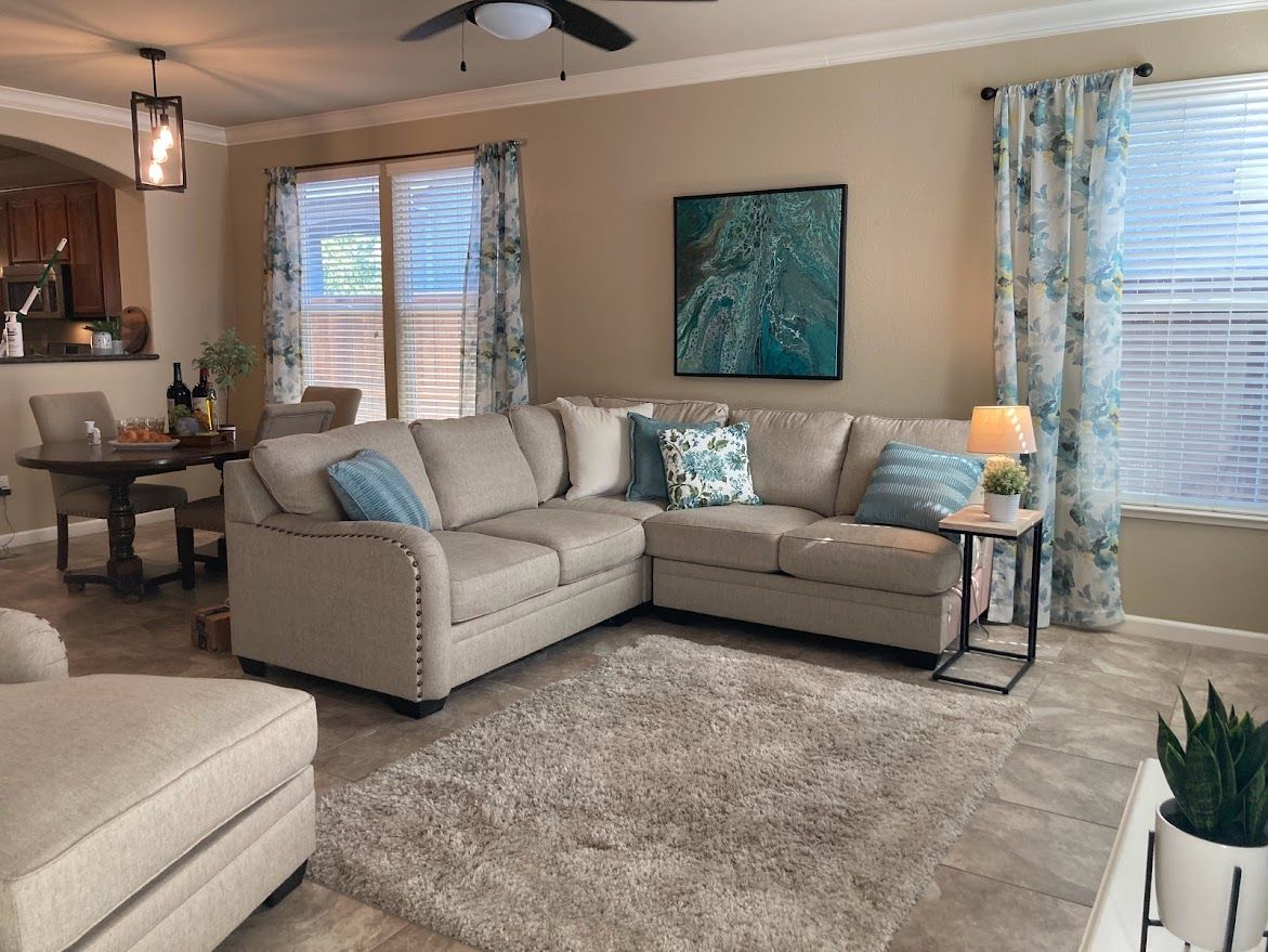 Cozy living room with beige sectional sofa, area rug, and blue accents, near a dining table.