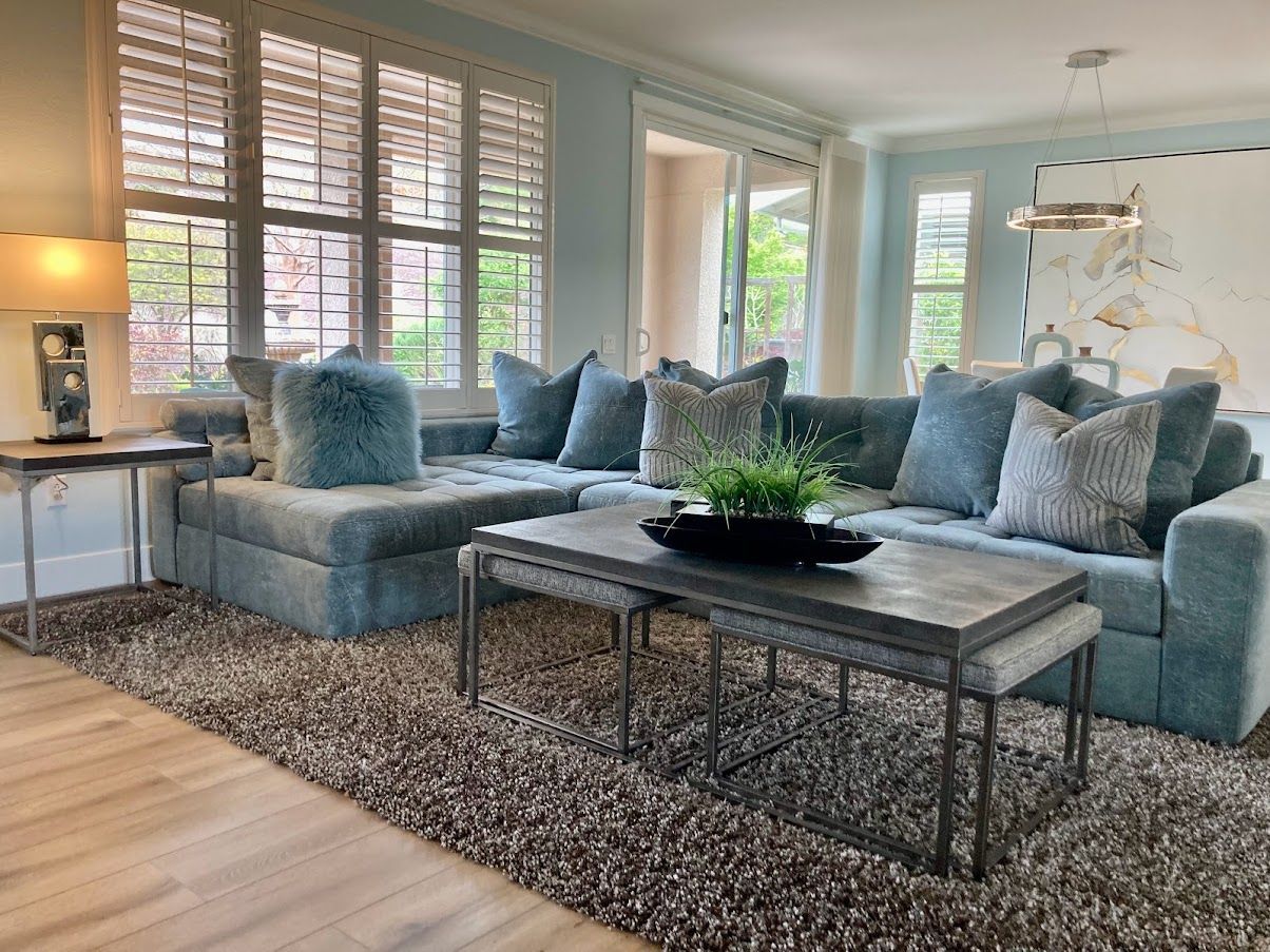 Living room with light blue sectional, gray rug, and matching coffee tables.