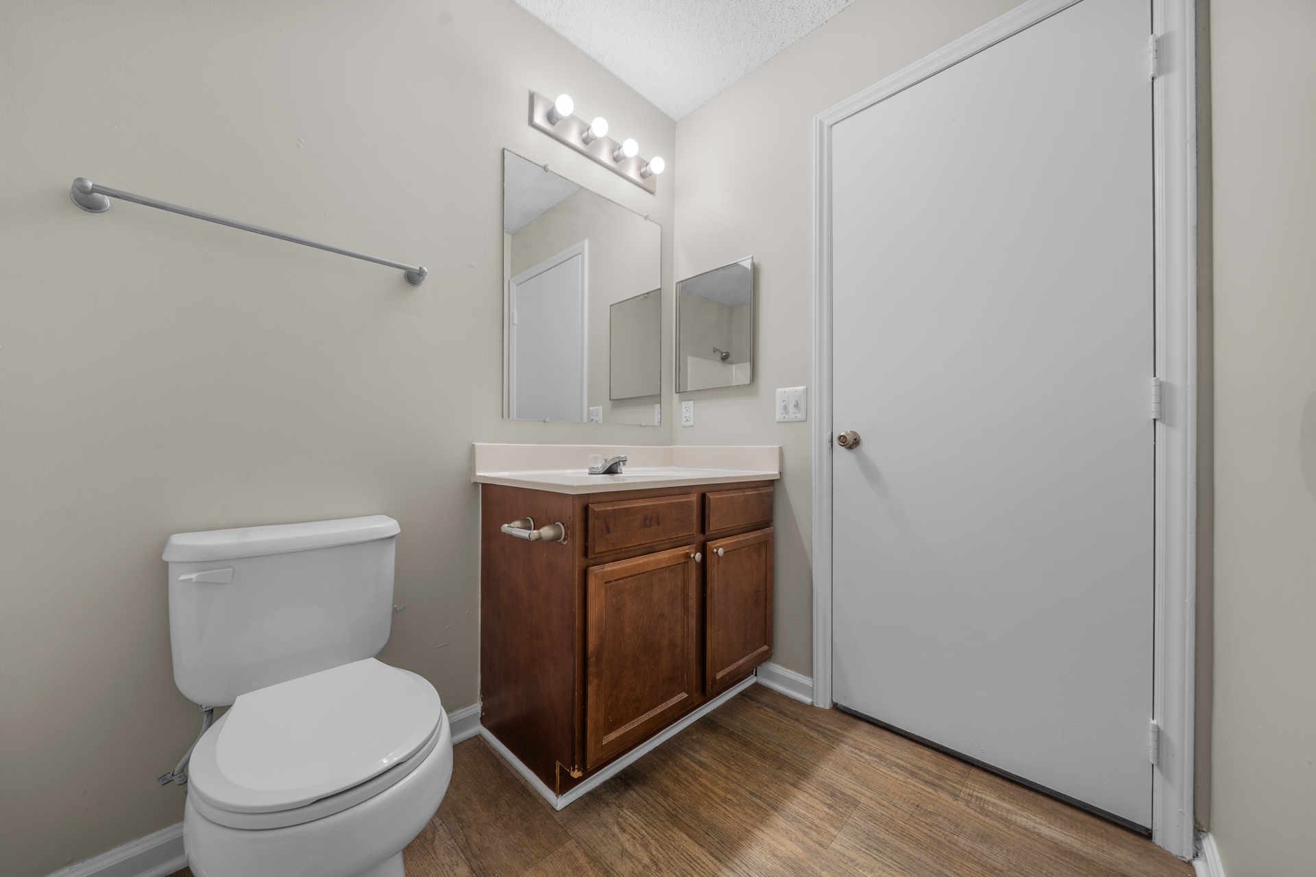 Bathroom with a white toilet, brown vanity, and light-colored walls and flooring.