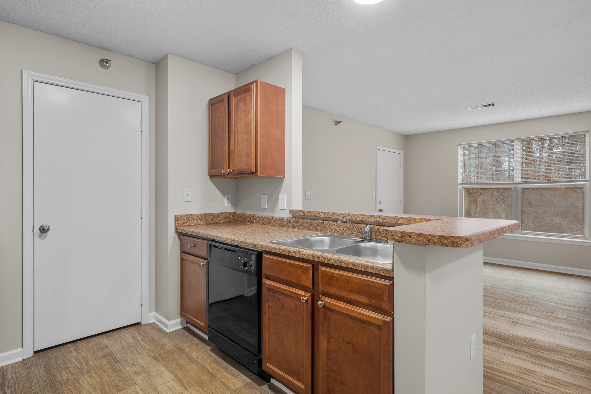 Kitchen with brown cabinets, black appliances, and a countertop overlooking an open living space.