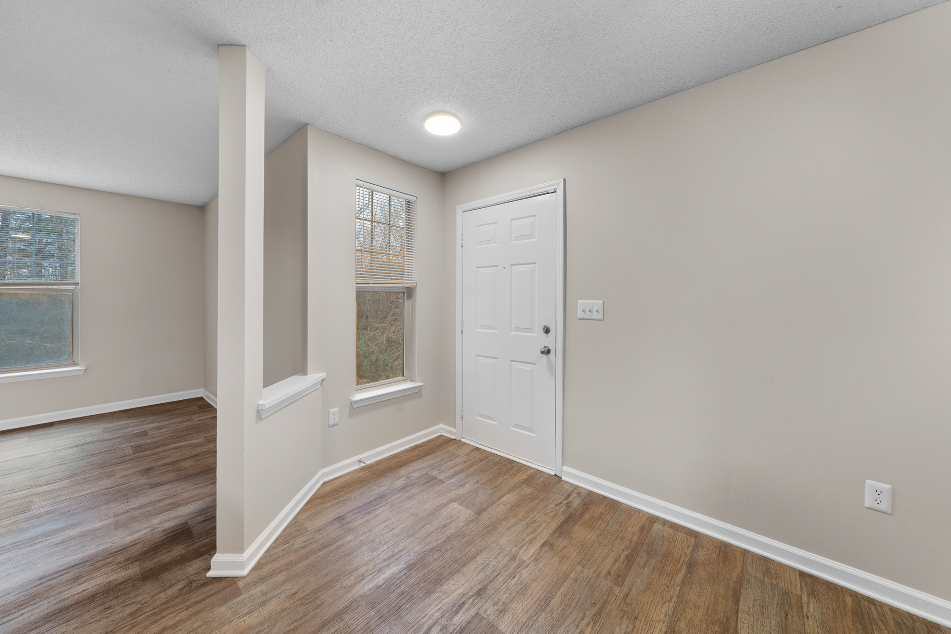 Interior entryway with a white door, light brown flooring, and beige walls.