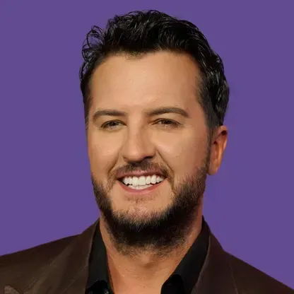Headshot of Luke Bryan smiling, wearing a dark blazer against a solid purple background.
