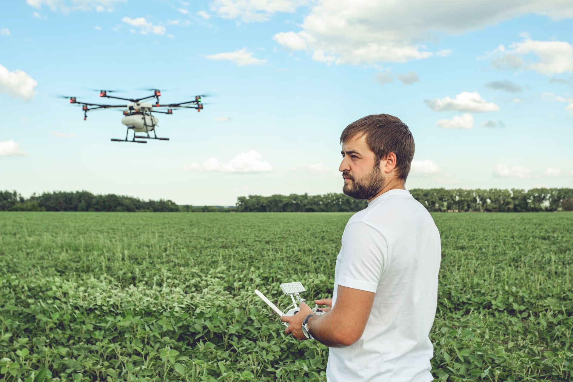 An aerial view of a person operating an octocopter drone over a field of corn crops with the text