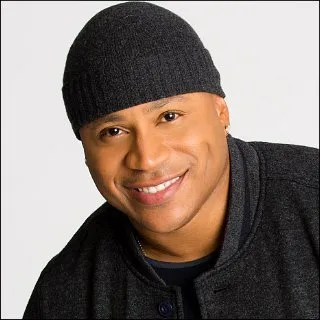 A man wearing a dark grey beanie and matching jacket smiles at the camera against a white background.