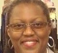 Woman wearing glasses and hoop earrings, smiling.