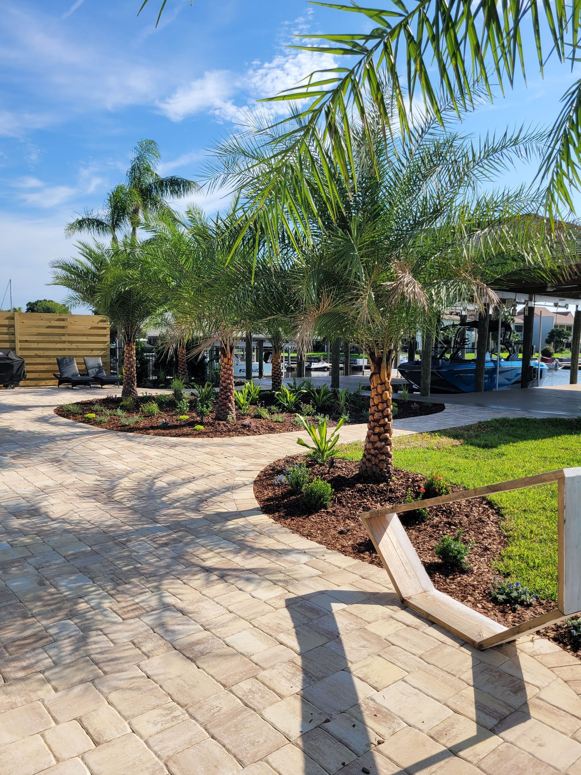 A brick walkway surrounded by palm trees and a swimming pool.