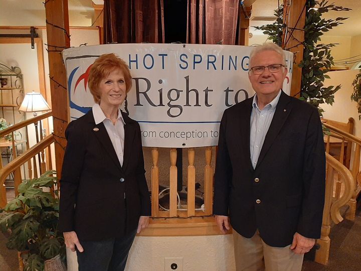 Two people stand in front of a banner that says