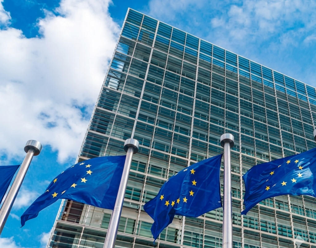 L'edificio della Commissione europea a Bruxelles, visto da un'angolazione bassa, con numerose bandiere dell'Unione europea che sventolano davanti.