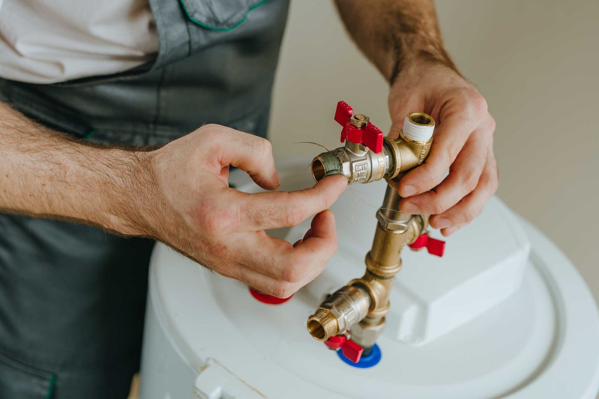 Close-up of a plumbing installation contractor fitting brass pipes and valves for a water boiler.