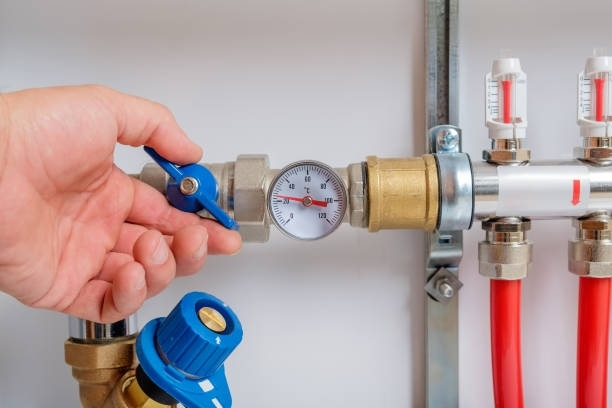A person is adjusting a valve on a water pipe.