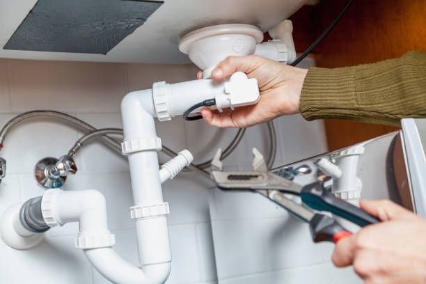 A person is fixing a sink with a wrench.