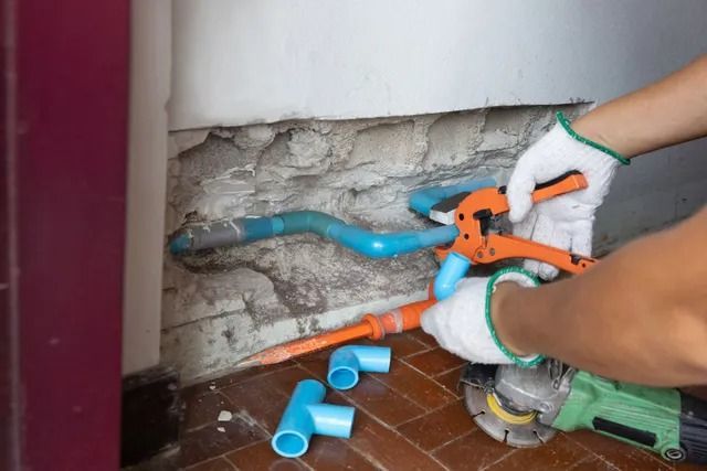 A person is cutting a pipe with a pair of pliers.
