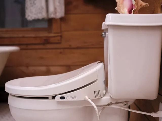 A white toilet in a bathroom with a seashell in the tank.