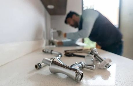 A plumber is fixing a sink in a kitchen