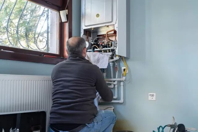 A man is working on a boiler in a room.