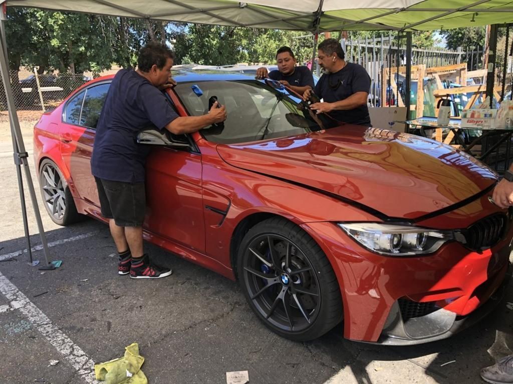 A group of men are working on a red bmw m3.