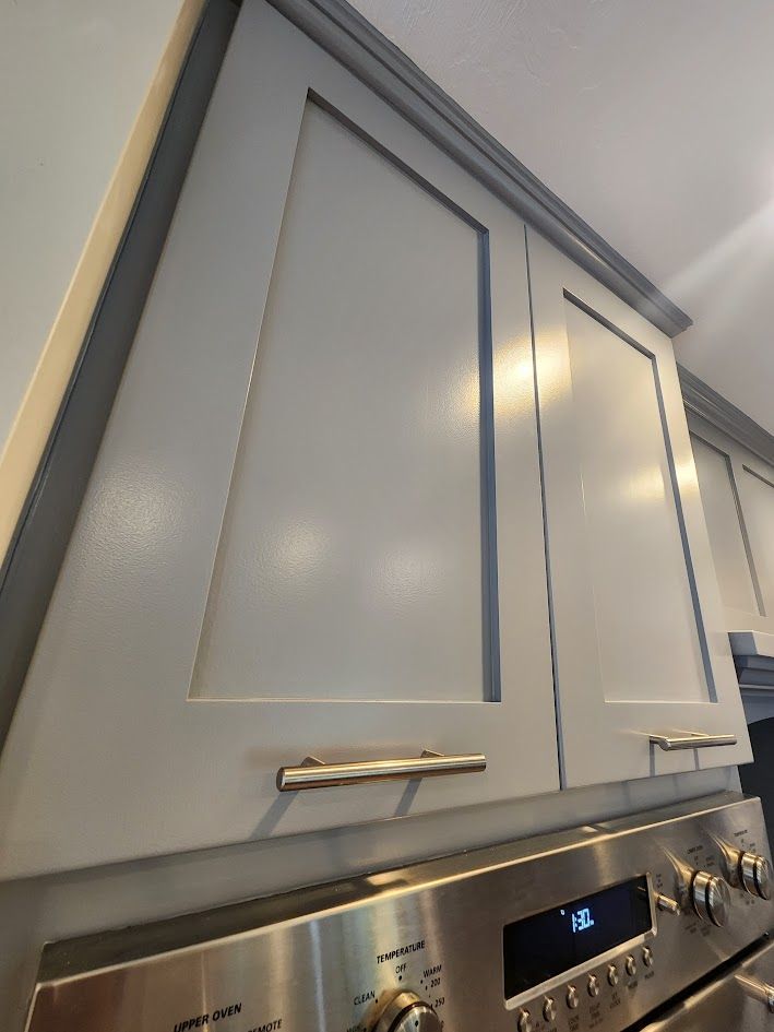 Gray kitchen cabinets above a stainless steel stove with a digital display and knobs