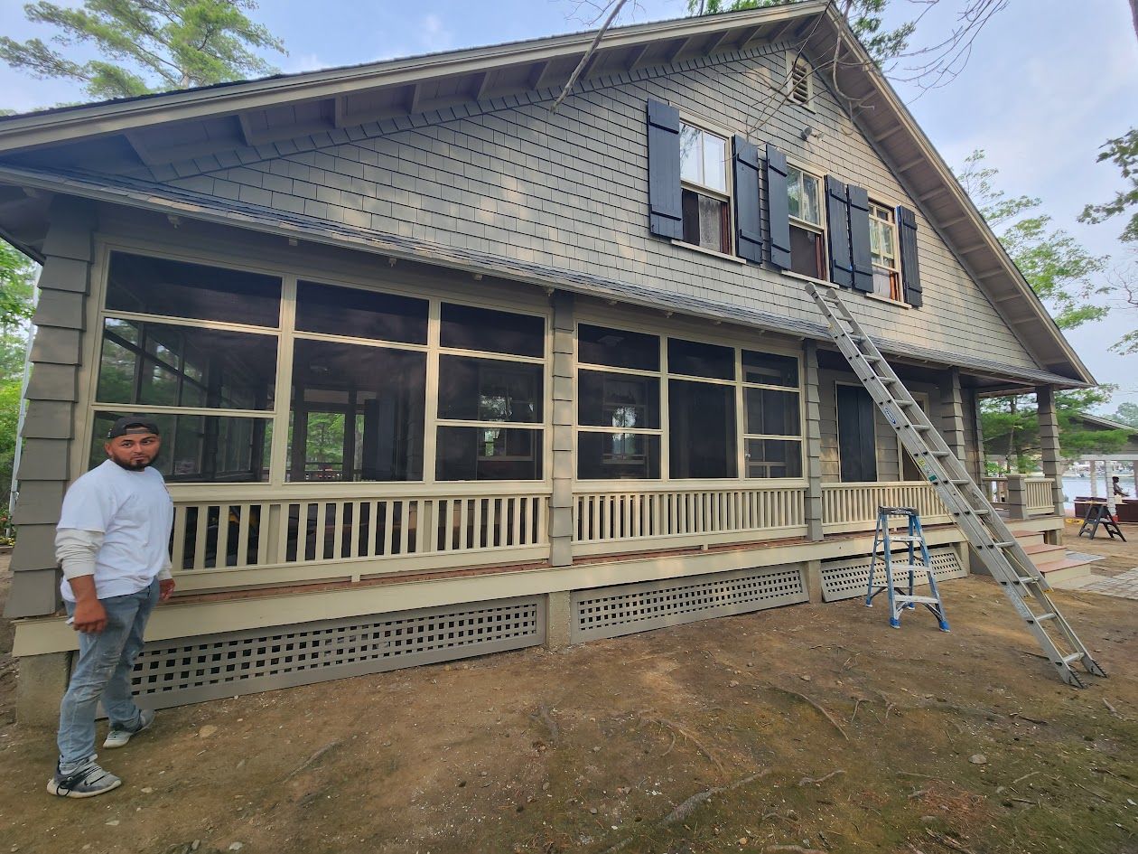 House exterior with workers, ladders, and scaffolding during siding or painting work