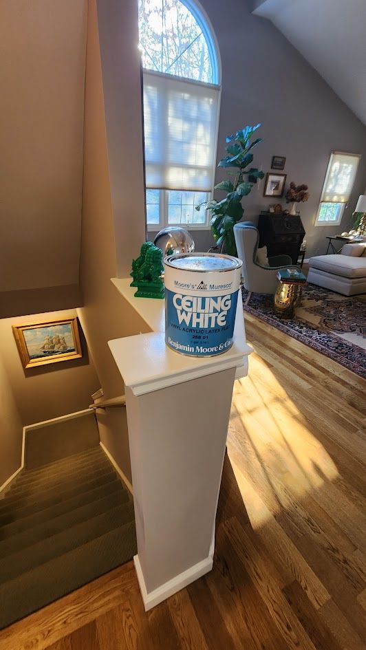 Blue “Thank You” tub on a white pedestal in a bright living room near a staircase
