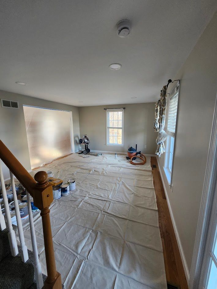 Empty room under renovation with floor covered in protective plastic and daylight from a window